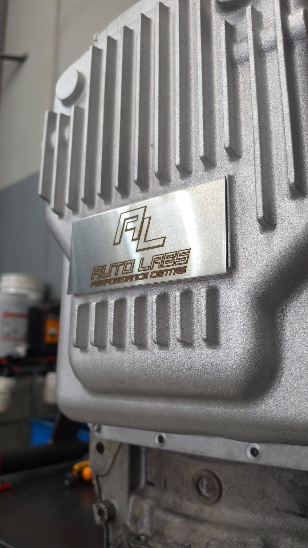 Close-up of the laser-etched Auto Labs plate on the finned lid of the 10R80 deep cast aluminium transmission pan