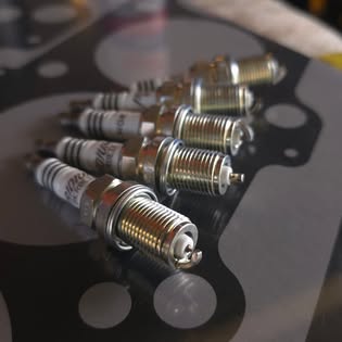 NGK-quality spark plugs on an engine gasket — genuine parts ready to install at Auto Labs Pakenham